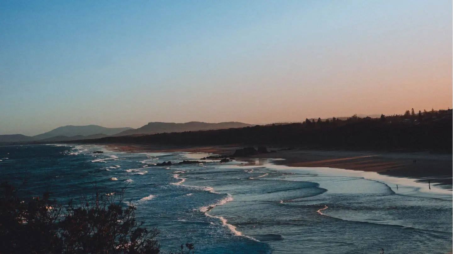 A shoreline at dusk under a pink and blue sky