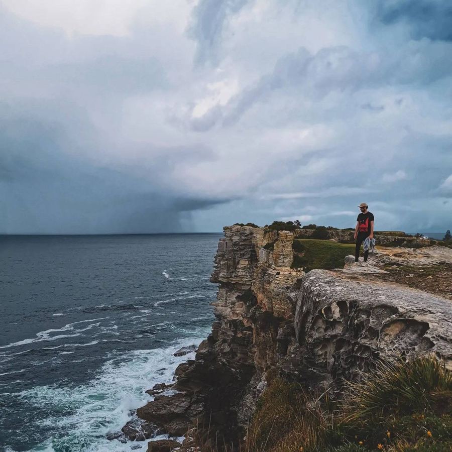 A figure on a stormy coastal cliff path